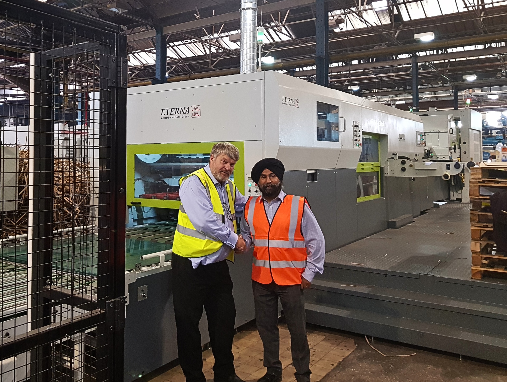 Mike Irving of M&K Trading and Jitha Singh of CBS Packaging shaking hands in front of the new Eterna E-Line